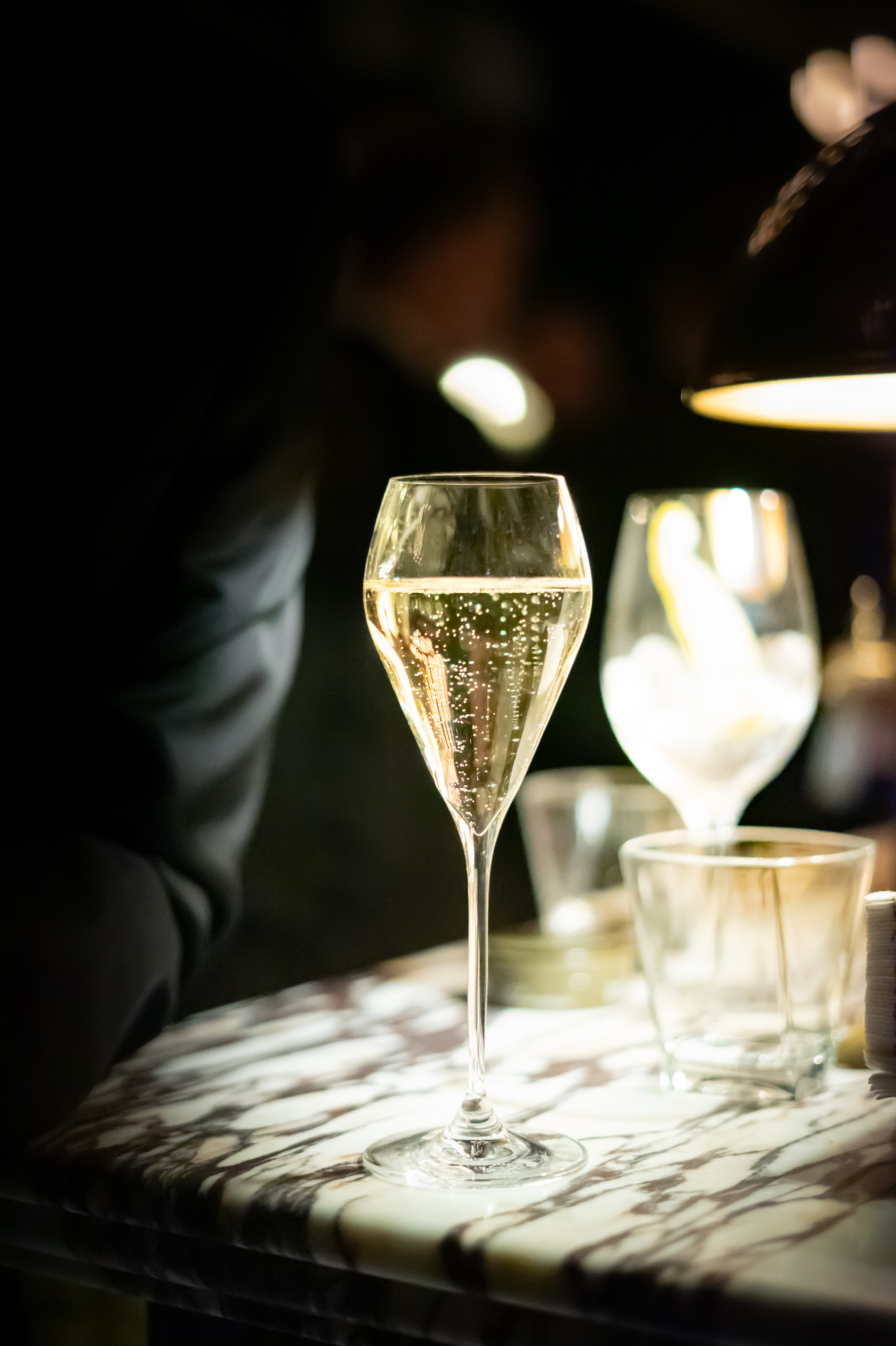 A glass of champagne on a marble table, lit warmly in a dim room